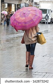 Woman Walking In Rain Down City Center High Street With Umbrella