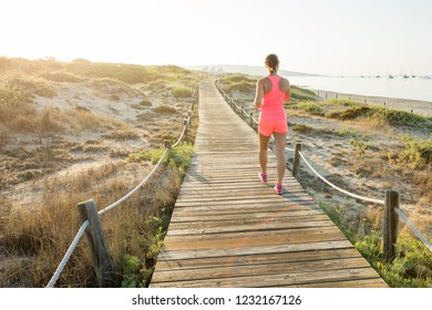 Woman walking, running on the wooden path along sandy beach. Migjorn beach, Formentera island. Spain. - Powered by Shutterstock