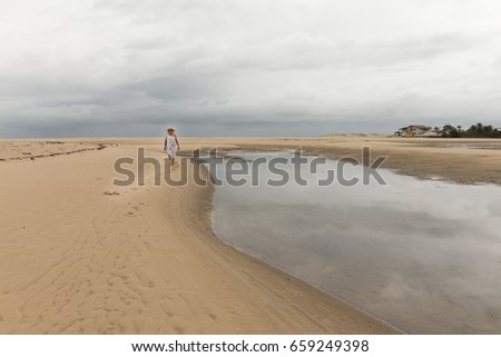 Woman walking in the sand of Barra do Rio beach - Rainy morning with dry moments.