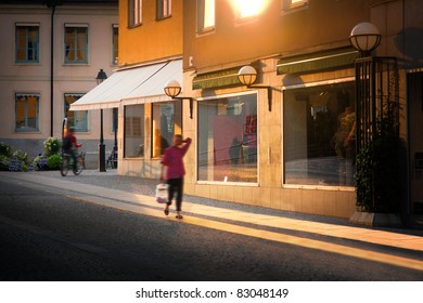 A Woman Walking With Shopping Bag In City At Sunset