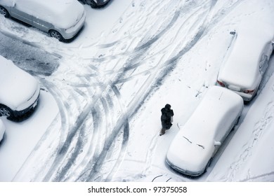woman walking snow covered ground and parked cars