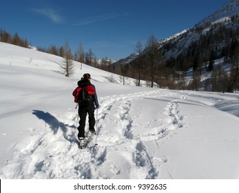 Woman walking in the snow with snowshoes on high mountain