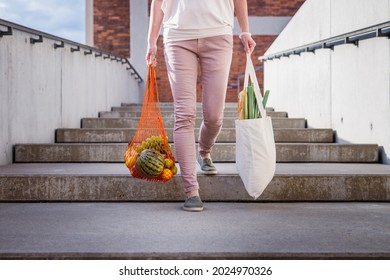 Woman Walking At Stairs And Carrying Reusable Mesh Bag After Shopping Groceries In City. Sustainable Lifestyle With Zero Waste And Plastic Free