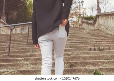 Woman walking up the stairs and taking / putting cellphone from / in the pocket.