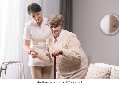 Woman With Walking Stick Assisted By Young Carer.