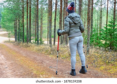 Woman with walking sticks on forest trail
