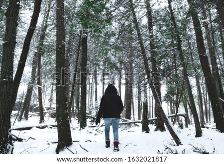 A woman walking through a blizzard in the forest. Snow flying towards POV. Have no fear, you're stronger than you know, weather the storm.