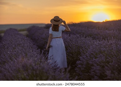 A woman is walking through a field of lavender flowers - Powered by Shutterstock