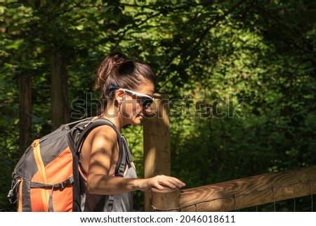 woman walking through the forest opening a wooden fence