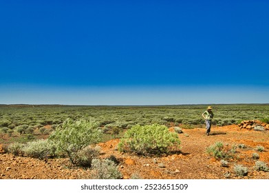 Woman walking in the vast expanse of the Australian outback, shire of Sandstone, Western Australia. Red earth and stunted trees
 - Powered by Shutterstock