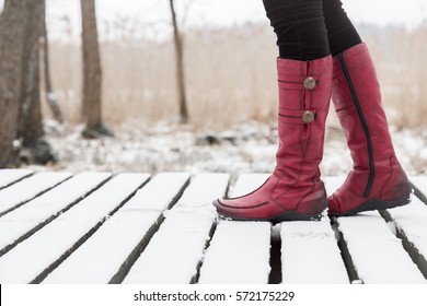 Woman walking in winter day.  Red winter boots on legs. Active lifestyle at nature.