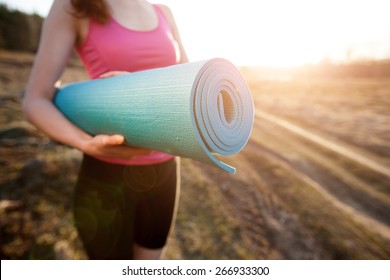 Woman Walking With A Yoga Mat Outside During Sunset N A Rural Area Wearing Sports Wear And Doing Yoga