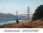 A woman walks along the Baker Beach with a Golden Gate Bridge in the background at San Francisco, California.