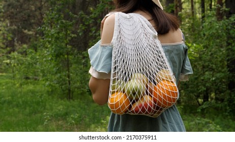 Woman Walks With A Braided String Bag Of Fresh Fruit. Life Without Plastic Waste. Low-waste Lifestyle. Sustainable Ecological Lifestyle