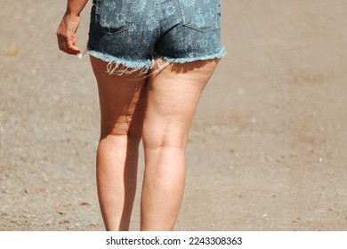 woman walks with her denim shorts and does not hide her cellulite.