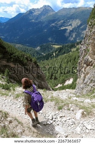 woman walks on the trail of european alps dolomites near precipice in summer