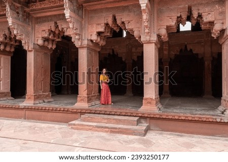 Woman walks through the great Agra Fort in Agra, India, with its wonderful architecture on a cloudy day