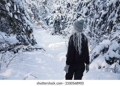 a woman walks through a snowy forest
