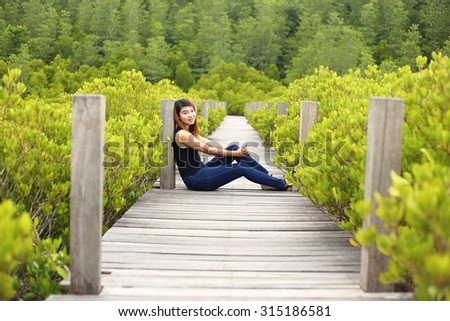 Woman and walkway made from wood and mangrove field