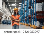 A woman warehouse inspector wearing a hard hat and safety jacket smiles broadly as they hold a clipboard. The brightly lit storage space highlights the precision of the warehouse arrangement.