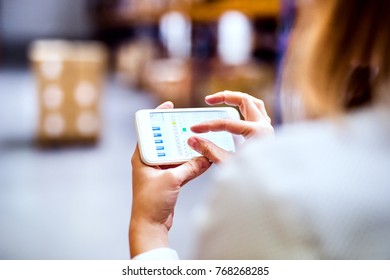 Woman warehouse worker with smartphone.