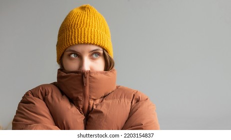 A woman in a warm jacket and hat sits on the bed at home and tries to keep warm. Home heating shutdown concept. Gas shutdown. - Shutterstock ID 2203154837