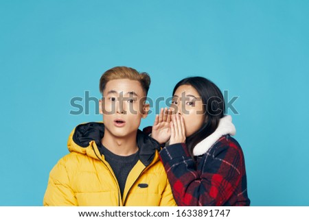 Woman in warm jacket something in the ear of a young man