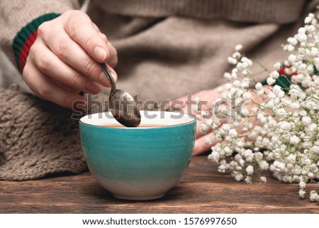 Woman in warm sweater drinking a hot tea close up background.