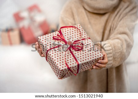 A woman in a warm sweater, holding a beautiful Christmas gifts. Holiday concept. Close up.