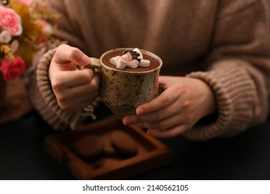 Woman in a warm sweater sipping hot dark chocolate topping with marshmallow candies. Warm and cozy. - Powered by Shutterstock