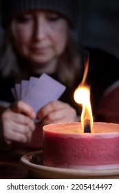 Woman With Warm Winter Clothes Is Playing Cards Indoors In Candlelight