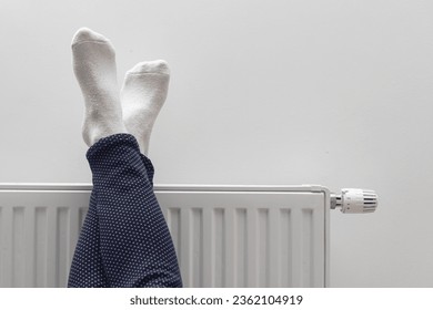 Woman Warming Up Her Feet On White Radiator At Home