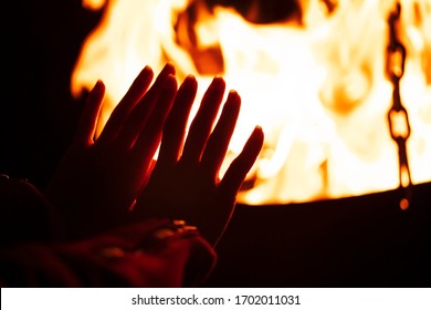 woman warming her hands by the campfire