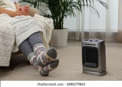 Woman Warming Legs Near Halogen Heater At Home, Closeup