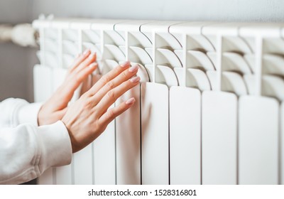 Woman warms up hands over heater. Concept of the need for good central heating. - Shutterstock ID 1528316801