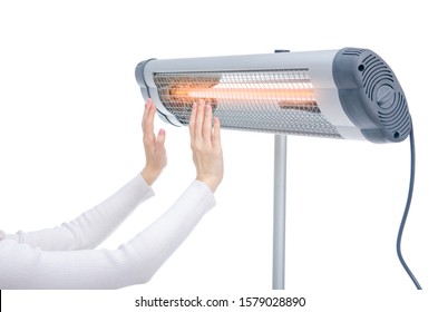 Woman warms her palms near an electric infrared heater on white background isolation