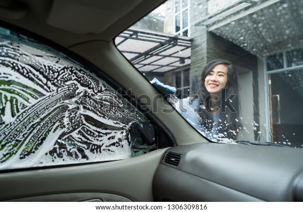 woman wash her car window with soap. shoot from\
inside the car