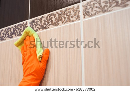 A woman washer is cleaning tiled surface in bathroom.