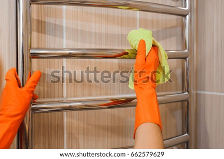 A woman washer is cleaning tiled surface in bathroom.