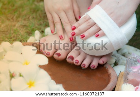 
Woman washes and cleans the feet in water clearing sponge and frangipani flowers in the garden,pink beige towels,Soap,Massage brush,Cosmetic bottles,Natural color,foot massage,spa,Health care,