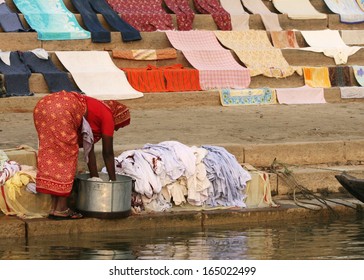 A Woman Washes Clothes Next To The Ganges River, In Varanasi, India.  Clothes Seem To Come Out Clean, Although The River Is Extremely Polluted.