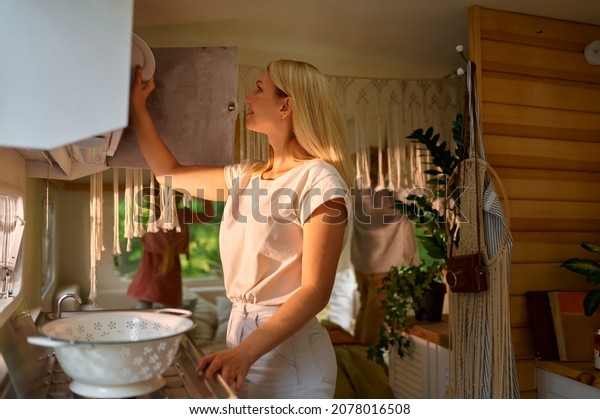 Woman washes\
dishes in a trailer, summer\
camping