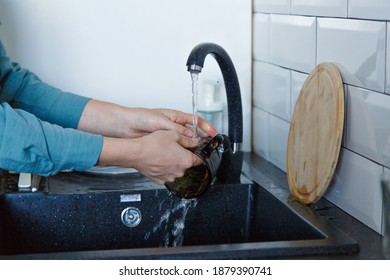 A Woman Washes Dishes. Washing The Cup In The Black Sink