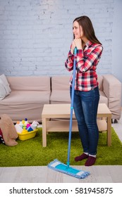 woman washes the floor, holding mop in her hand, standing in room. Household chores