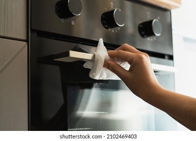 A Woman Washes The Handle Of A Dirty Oven With A White Napkin. Horizontal View.