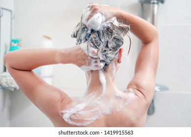 Woman washes her hair with shampoo in bathroom. Woman washing her hair with a lot of foam inside a shower. Back view of young woman washing her hair. Close-up. - Shutterstock ID 1419915563