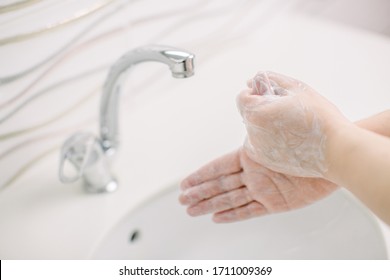 Woman washes her hands by surgical hand washing method. She washes his hands for at least 20 seconds. She washes his thumb. She washes her hands to protect her from Covid-19. - Shutterstock ID 1711009369