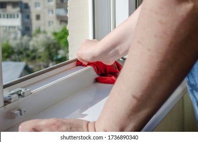 Woman Washes A Window And Window Sill With A Red Rag