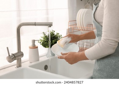 Woman washing bowl at sink in kitchen, closeup - Powered by Shutterstock