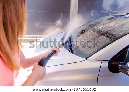 Woman washing car with pressure washer at self-service car wash station